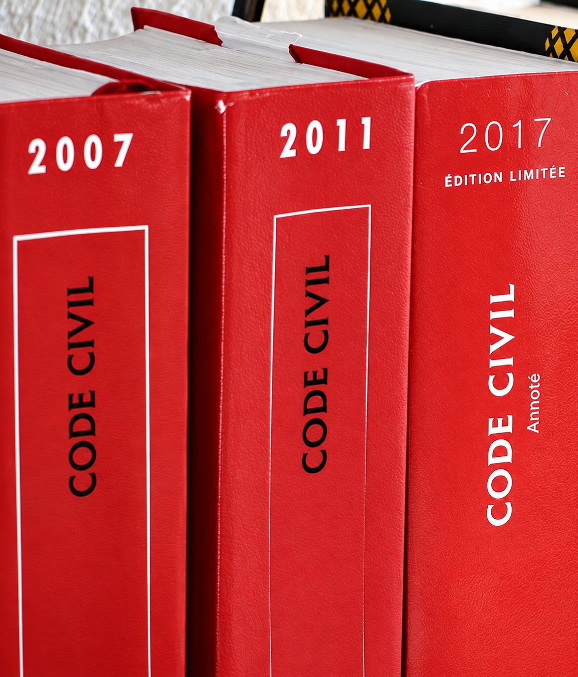 Trois codes civils à la couverture rouge, éditions 2007, 2011 et 2017, alignés côte à côte.