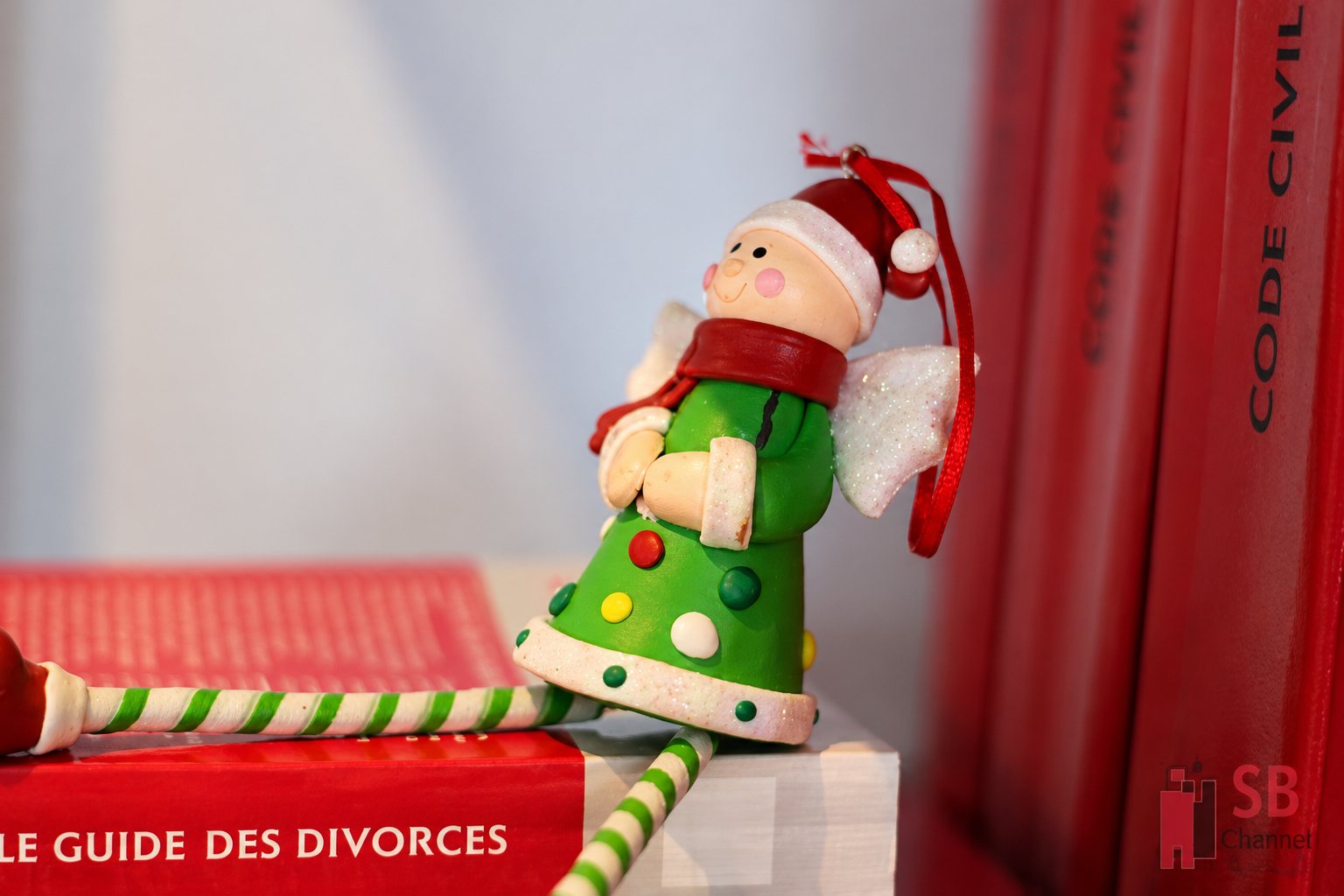 Figurine d’ange de Noël assise sur un livre rouge, devant des codes civils rouges.